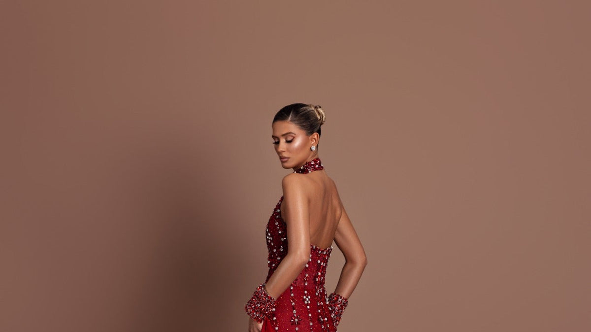 Model in a red crystal-embellished Dodona Avdiu gown with a long train