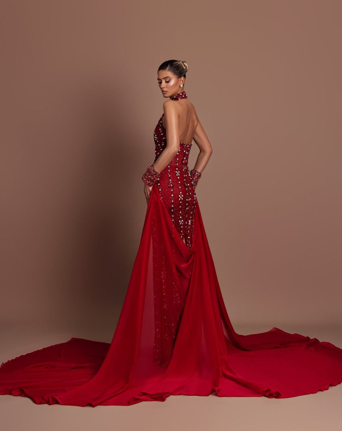 Model in a red crystal-embellished Dodona Avdiu gown with a long train